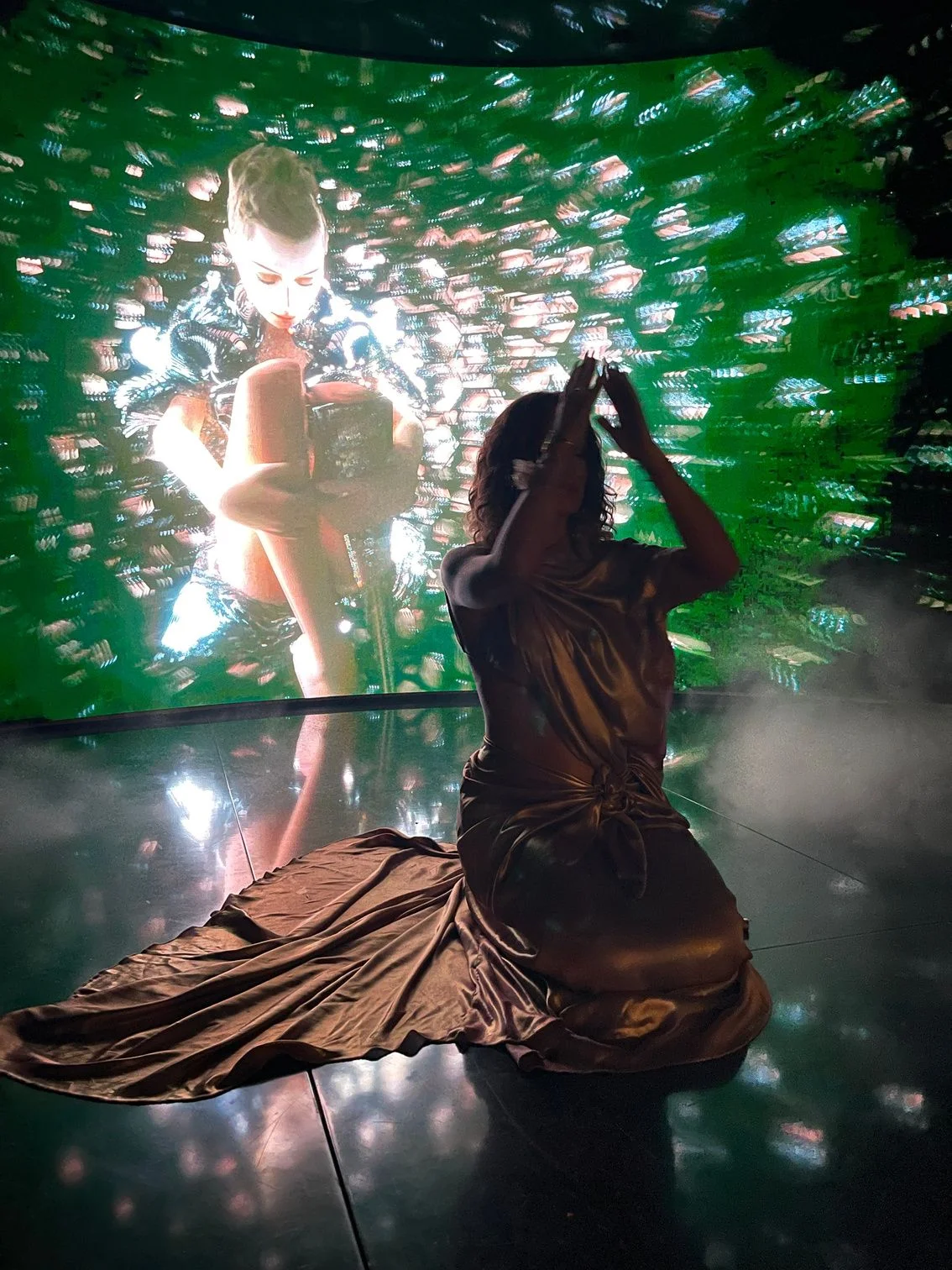 Aimée Sophia seated before an immersive LED installation